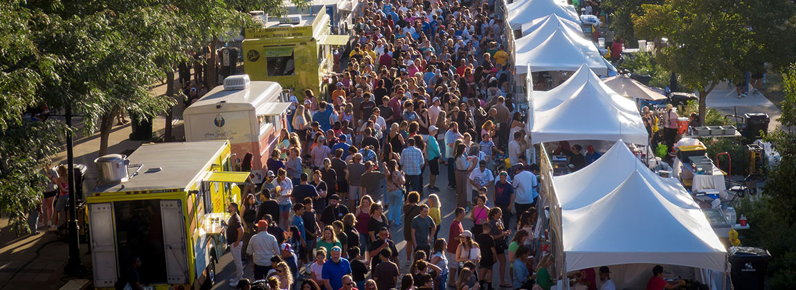 An overhead view of a crowd on a street filled with food trucks and people